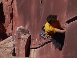 MS ZO Looking down onto climber clipping piece of gear into rock abd Climber looks up towards oncamera and takes one hand off rock / Indian Creek, UT, USA Stock Footage