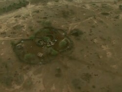 Wide Shot - Maasai village huts are close to each other in a barren savanna area / Kenya Stock Footage