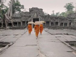 WS Buddhist monks with parasols walk through the courtyard of an ancient temple in Angkor Wat / Siem Reap, Cambodia Stock Footage
