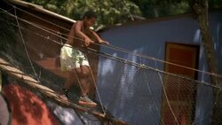 Young Brazilian boy runs across swinging rope bridge in Rio slum Stock Footage