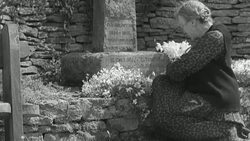B/W Mourner arranging flowers before war memorial / United Kingdom Stock Footage