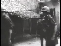 B/W 1960's soldiers walking past camera in village / Vietnam / SOUND Stock Footage