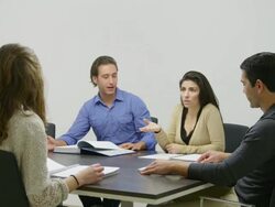 WS modern office interior group of people (two men, two women) in glass-enclosed meeting room seated at table engaged in conversation Stock Footage
