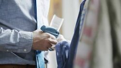 Shop employee tags shirts in clothing store with tagging gun Stock Footage