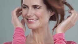 Portrait of woman 40yrs + laughing and touching hair blowing in wind Stock Footage