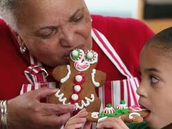 CU Grandmother and Granddaughter Eating Gingerbread Men Cookies in Kitchen / Richmond, Virginia, USA Stock Footage