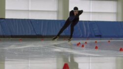 MS SLO MO Long track speed skater coming around corner on track in arena Stock Footage