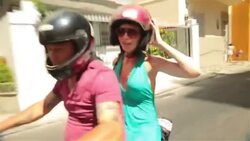 Mototaxi driver points out sights to passenger in blue dress and gives thumbs up while navigating through the streets of Rio Stock Footage
