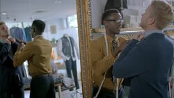 Clothing store clerk hangs measuring tape over neck and adjusts customer's collar Stock Footage