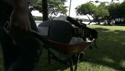 A boater transports a boat motor using a wheelbarrow. Stock Footage