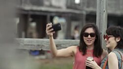 Two young women pose for a smartphone selfie and laugh together in Texas ghost town Stock Footage