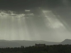 Shards of sunlight through dark cloud, over looking a hilly, Moroccan landscape. Stock Footage