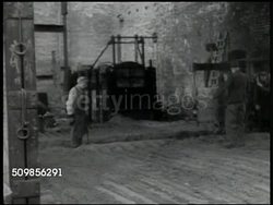 1946: BRITISH ZONE, GERMANY: RUHR DISTRICT: HA WS Krupp steel factory w/ smokestacks smoking. Railroad coal cars in factory yard. Worker pushing ladle of molten metal, workers helping pour hot metal into mold. Post WWI war reconstruction. Instructional Video