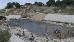 Locals relax and splash in a shallow reservoir. Stock Footage