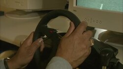 A man turns a steering wheel while using a computer screen to simulate the driving of a taxicab. Stock Footage