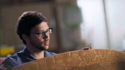 Young artisan runs hand along smooth curve of wooden longboard in workshop Stock Footage