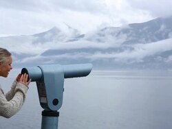 Woman pauses besides viewing scope, looks across lake Stock Footage