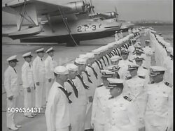 1940: US AIR CORPS: US Navy officers walking line of sailors (all in dress whites) standing in front of seaplane Patrol Bomber 2P3. MS TRACKING seaplane Patrol Bomber (3P10) taking off from water.  Patrol Bombers in line flight, graduated altitudes. Instructional Video