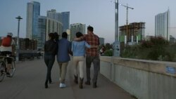 Group of friends walk across Pfluger Bridge towards downtown Austin, Texas at sunset Stock Footage