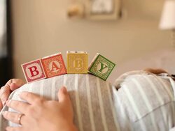 A pregnant women using blocks to spell the word BABY on her stomach. Stock Footage