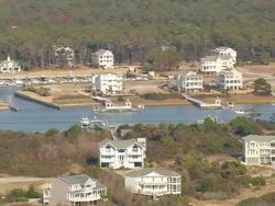 MS AERIAL Shot of wooden houses surrounded by trees bank of river at Holden beach / North Carolina, United States Stock Footage