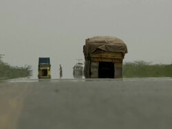 Trucks on the road and man crossing it Stock Footage