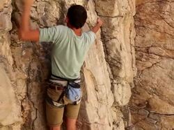 Handheld shot of a rock climber feeling his way up a cliff. Stock Footage