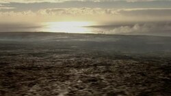 Across a barren lava field, a plume of volcanic steam rises from the coast of Hawaii's Big Island. Stock Footage