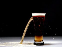 MS SLO MO Glass of beer breaking and splashing against black background / Vieux Pont, Normandy, France Stock Footage