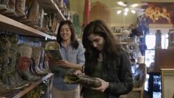 Excited group of friends walk through Western store looking at cowboy hats and boots and taking smartphone photos Stock Footage