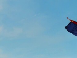 Wide shot young blonde woman in mask, cape, and superhero costume in midair simulating flying after jumping on trampoline Stock Footage