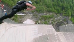 BASE jumper plunges down concrete dam face Stock Footage