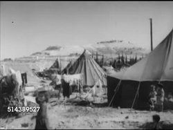 1952: MANDELBAUM GATE: WS (POV Jordan side) Car driving down through checkpoint anti-tank cone maze. ARAB-ISRAELI WAR REFUGEES: VS Palestinian Arabs in tent city, hanging laundry, family putting tent together, young woman sewing edges. Instructional Video