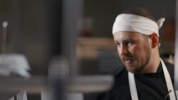 Head chef reads meal orders out loud and directs kitchen staff in restaurant kitchen Stock Footage