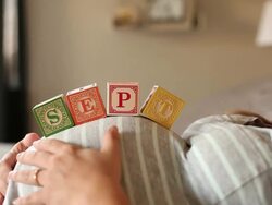 A pregnant women using blocks to spell the month of SEPT on her stomach. Stock Footage
