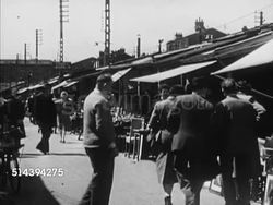 1950: FLEA MARKETS: PARIS, FRANCE: WS Narrow streets of Paris w/ buildings. VS Tourists, people, shopping at outdoor flea market, couple looking at lamp. Instructional Video