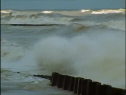 MWA Pan left, Stormy waves crashing on to beach, past sea defences to erode beach, USA Stock Footage