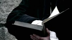 A robed man flips through a book and looks around thoughtfully. Stock Footage