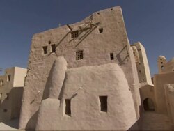 Wide Shot,  - Palm trees wave in the wind next to a sandstone home in Egypt Stock Footage