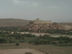 Moroccan dwellings sit upon a hill, surrounded by land and vegetation.  Stock Footage