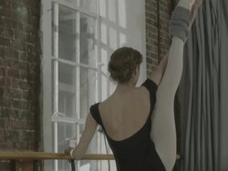 Ballerina stretching at ballet bar in dance studio Stock Footage