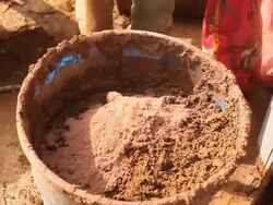 CU TU TD Carpenter adding clay and water before hand mixing adobe mud during framing of an energy efficient post / Grass Lake, Michigan, USA  Stock Footage