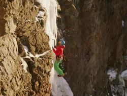 MS PAN Shot of ice climber going up steep pillar of ice surrounded by rock and snow / Cody, Wyoming, United States Stock Footage