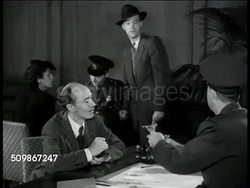 1947: U.S. COUNTERFEITS: IMMIGRANTS: MS Immigrants on line, custom officers. MS Immigrants seated at tables, passport check. DRAMATIZATION: VS Immigrant having US currency, money, bills inspected, men checking, '...all counterfeit... money no good.' Instructional Video