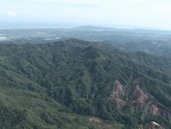 Aerial over jungle covered hills showing bare patches of deforestation, Kota Kinabalu, Malaysia Stock Footage