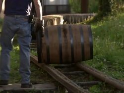 Telephoto close up of employee rolling a barrel of bourbon on to rail line. Stock Footage