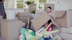 Smiling girl hugging stuffed alligator under moving box Stock Footage