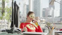 Superhero talking on cell phone at desk in office Stock Footage