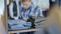 Modern shop worker counts stock and enters numbers on tablet in clothing store Stock Footage
