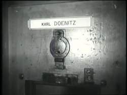 A guard looks through a peephole on a door labeled H. Goering. News Clip